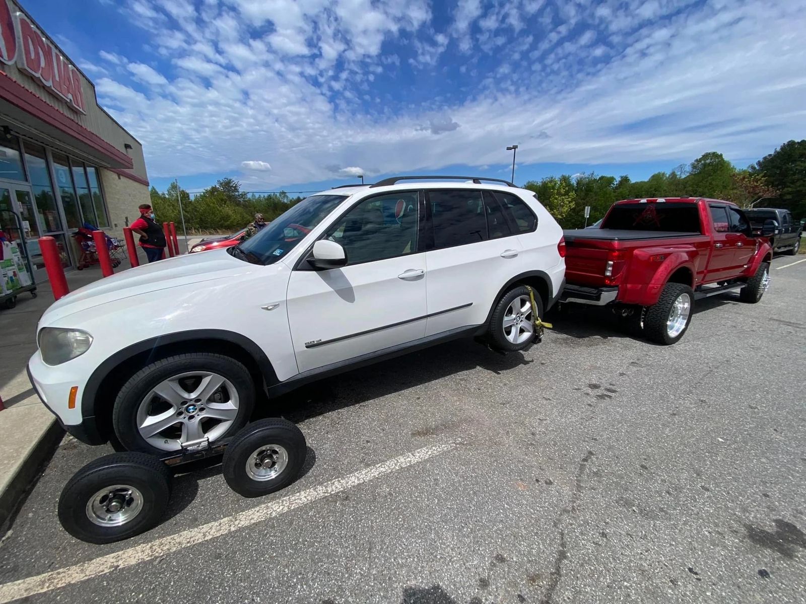 White BMW SUV on wheel dollies behind the red Big Toe's dually