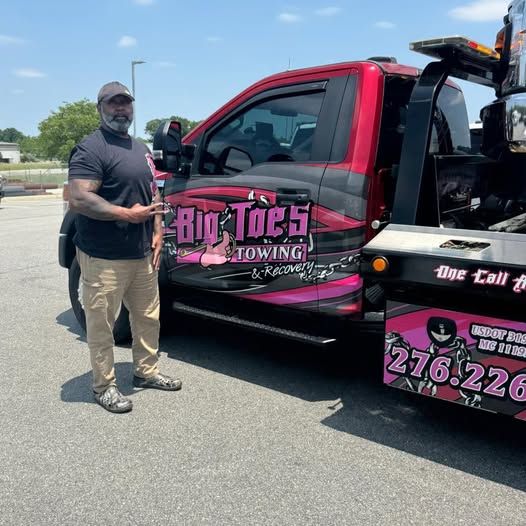 Big Toe standing beside his pink Big Toe's Towing & Recovery truck